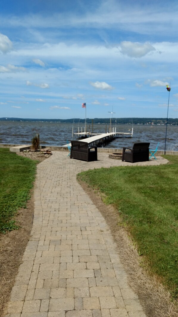 A paved walkway leading to a dock with benches and a flagpole.