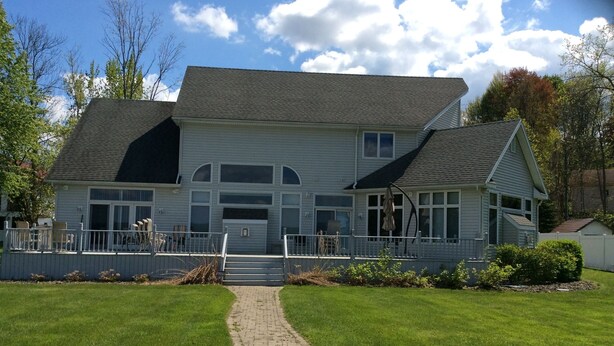 A two-story house with a covered porch and a brick pathway leading to the entrance.