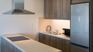 A modern kitchen with wooden cabinets, a stainless steel range hood, a built-in oven, a refrigerator, and a double sink.
