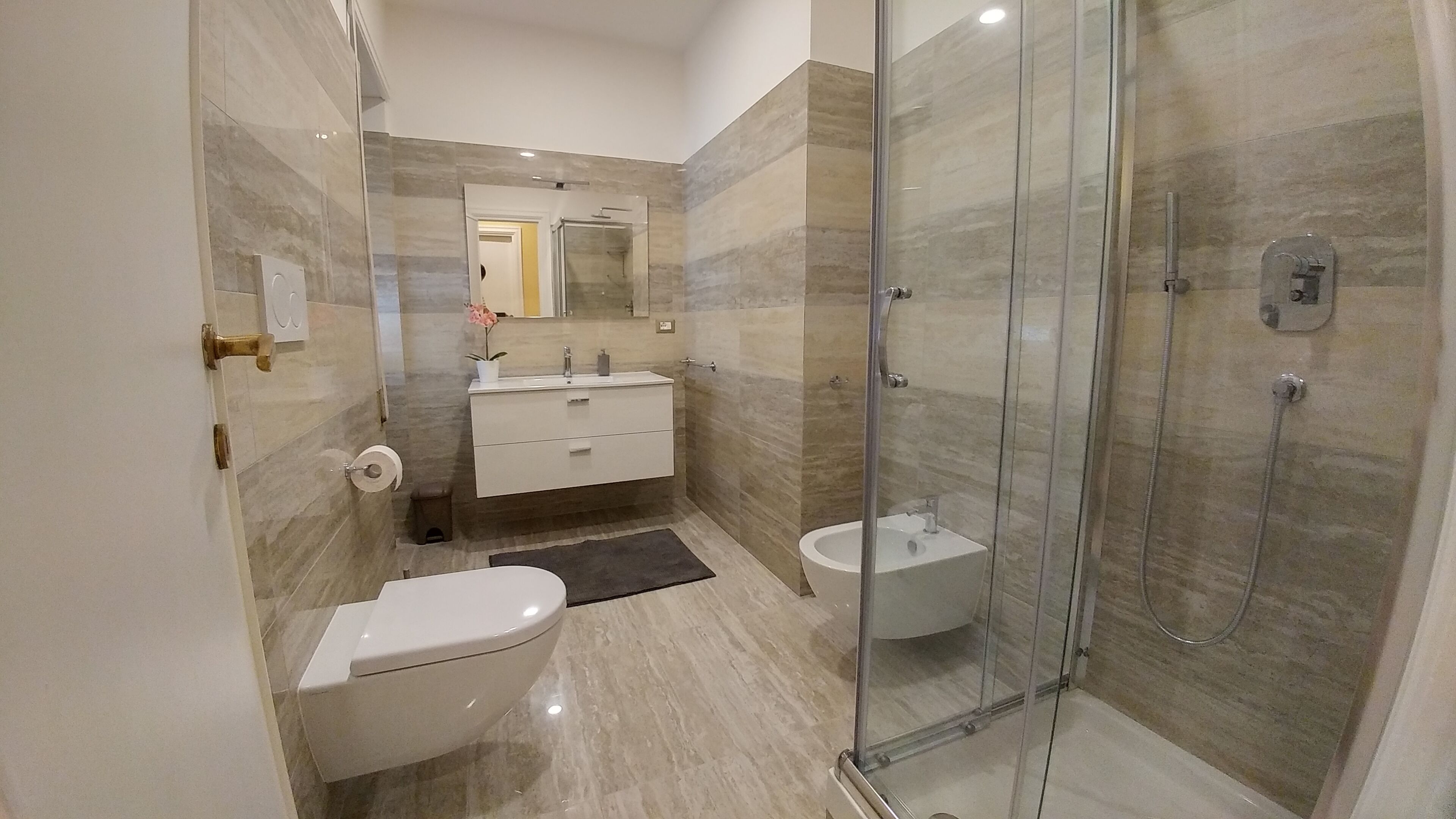 Une salle de bain moderne équipée de toilettes, d’un bidet et d’une douche à parois de verre.