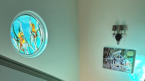 A staircase with a stained glass window depicting sea creatures, a wall-mounted picture of a building, and a wall-mounted light fixture. - Beautiful ocean retreat (Morro Bay)