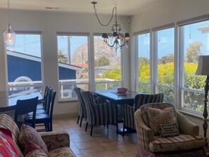 Ein geräumiger Essbereich mit Tisch und Stühlen, große Fenster mit Blick ins Freie und eine darüber hängende Chandelier.