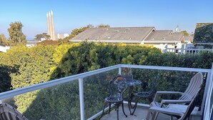 A balcony with outdoor furniture, including chairs and a table, overlooking a residential area with houses and greenery. - Beautiful ocean retreat (Morro Bay)