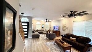 A living room with a sectional sofa, a coffee table, a TV, and a ceiling fan.