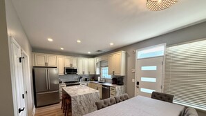 A modern kitchen with marble countertops, stainless steel appliances, and a dining area with a marble island and cushioned chairs.