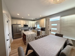 A modern kitchen with marble countertops, stainless steel appliances, and a dining area with a marble island and cushioned chairs.