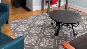 A room with a round table, a red chair, a TV mounted on the wall, a patterned rug, and a wooden dresser. - Quiet, Spacious Apt in the Heart of Marquette! (Marquette)