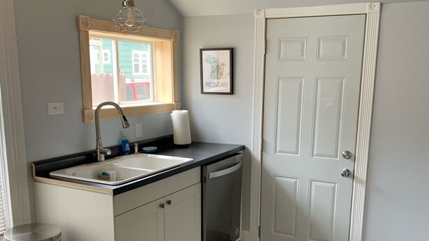 A kitchen with a sink, dishwasher, and a window with a view of a green building. - Quiet, Spacious Apt in the Heart of Marquette! (Marquette)