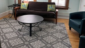 A living room with a brown sofa, a round table, and a patterned rug. - Quiet, Spacious Apt in the Heart of Marquette! (Marquette)