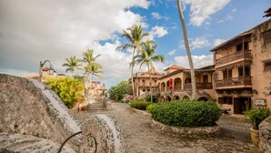 A historic building with a courtyard, palm trees, and a stone wall. - Beautiful sea view Golf Villa in Casa de Campo (La Romana)