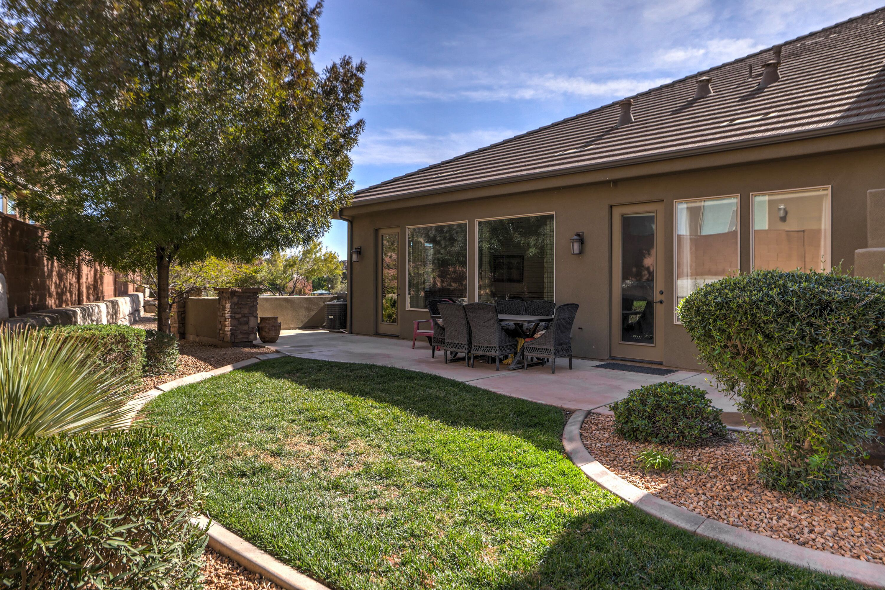 Una casa residencial con patio, mobiliario exterior y un césped bien cuidado.