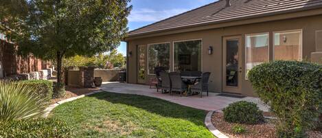 Una casa residencial con patio, mobiliario exterior y un césped bien cuidado.