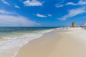 A beach with a clear sky, sandy shore, and a few umbrellas.