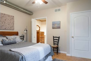 Un dormitorio con cama, cómoda, silla y una puerta.