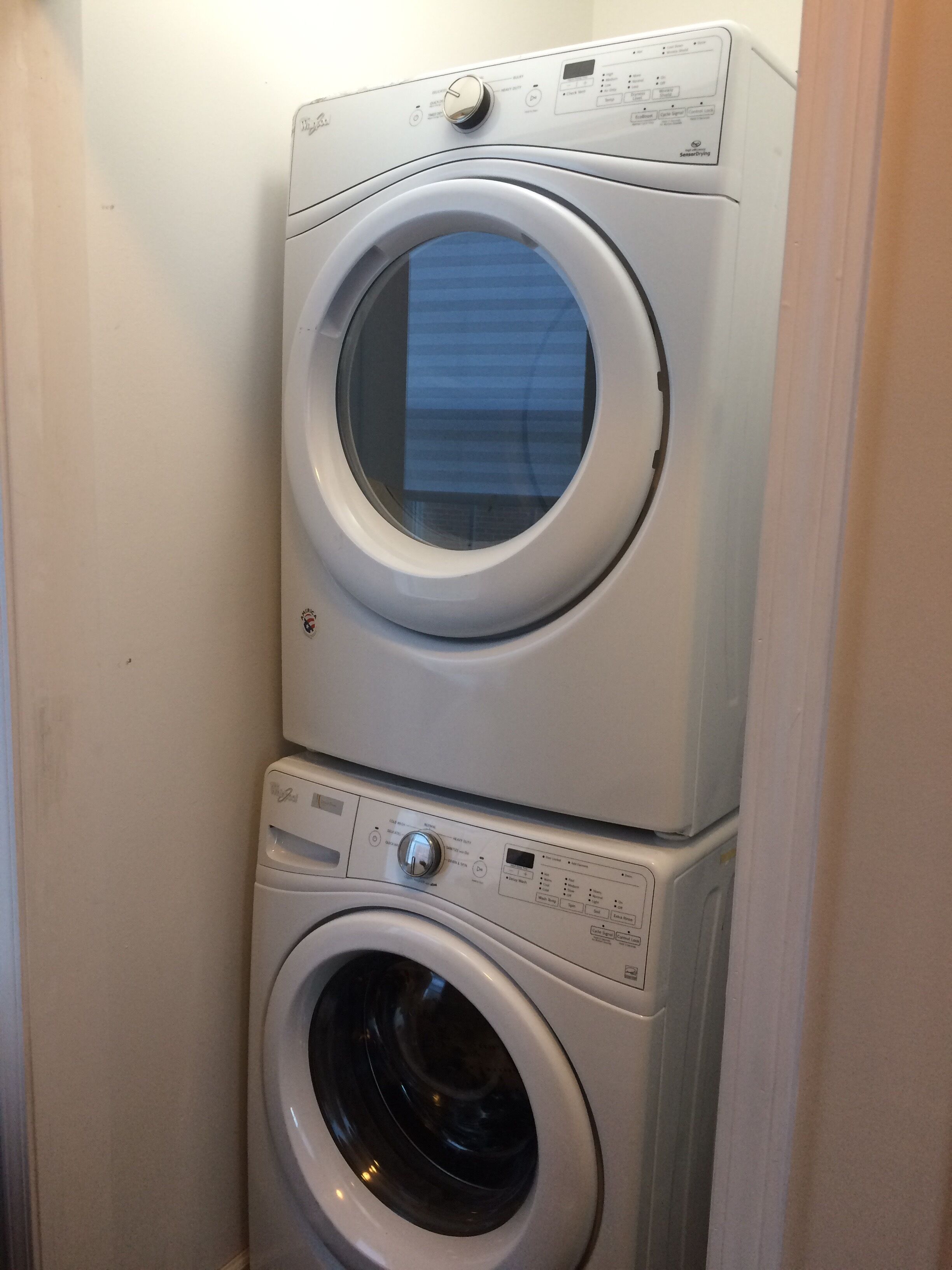 Une machine à laver et un sèche-linge superposés dans une buanderie.
