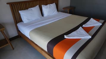 Una cama bien tendida con sábanas blancas y una colcha a rayas, un cabecero de madera y dos mesitas de noche.