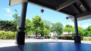 An open pavilion with a tiled floor and a clear view of the surrounding area, including trees and parked cars. - Maihom Resort Dechatiwong Bridge (Nakhon Sawan)