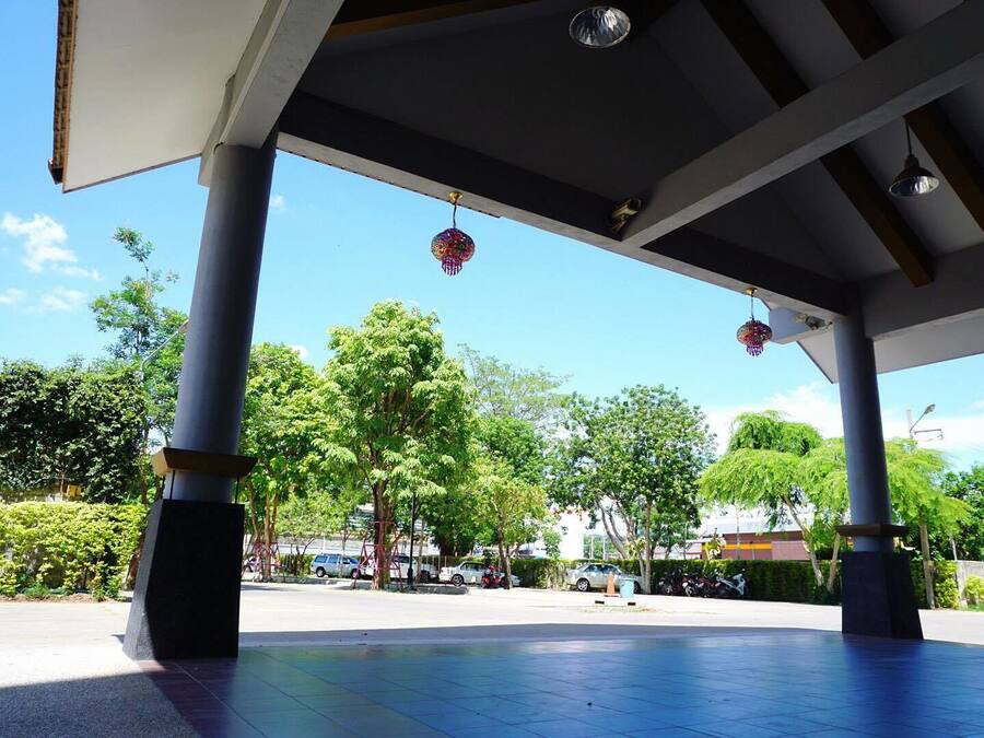 Un pabellón abierto con suelo de baldosas y vista despejada del entorno, incluyendo árboles y coches estacionados.