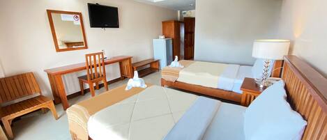Habitación de hotel con dos camas, un escritorio, una silla, un televisor y una lámpara.