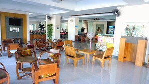 A spacious lobby with wooden furniture, a reception desk, and a television mounted on the wall. - Maihom Resort Dechatiwong Bridge (Nakhon Sawan)
