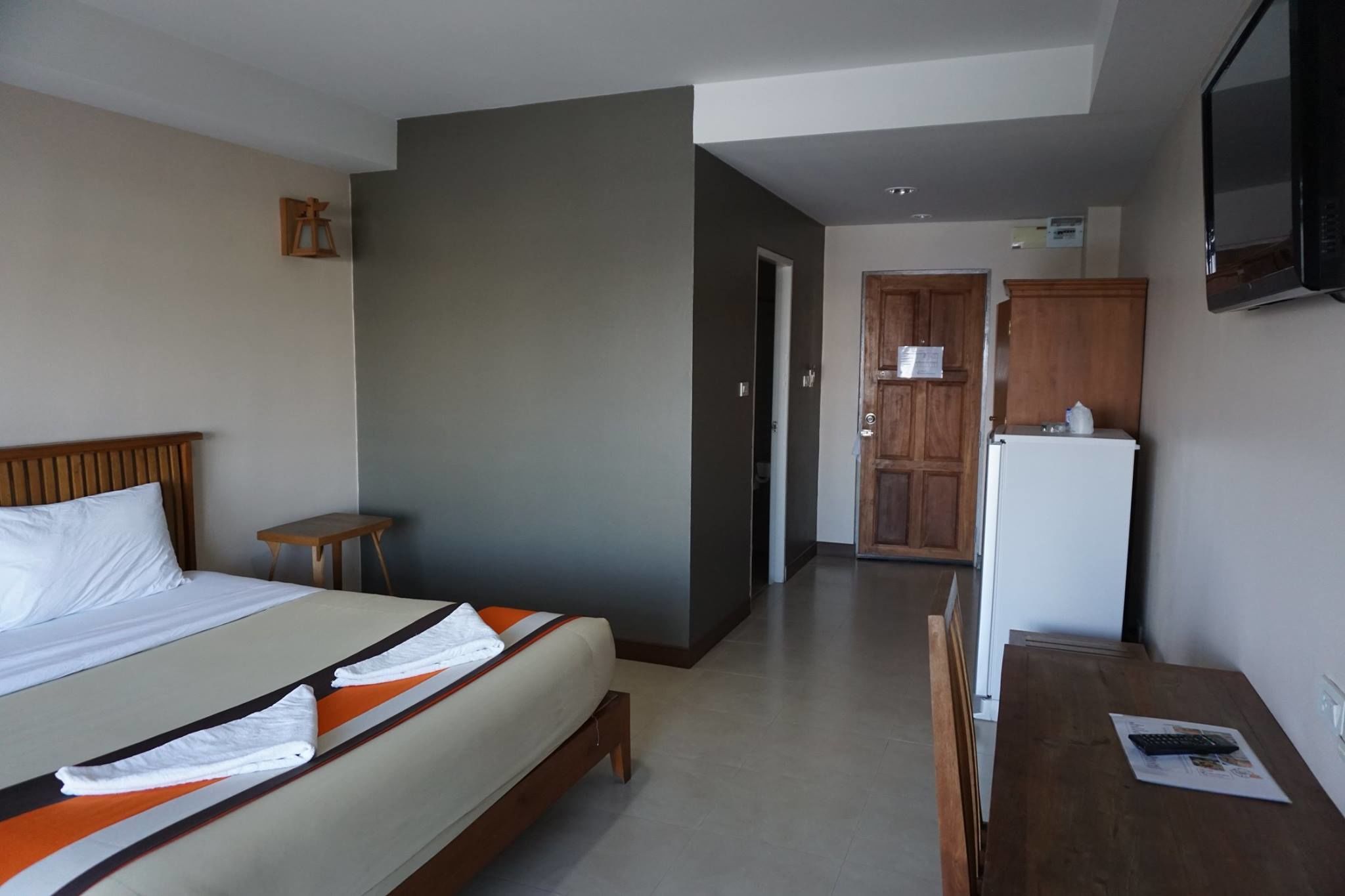 A hotel room with a bed, a small table, a refrigerator, and a television.