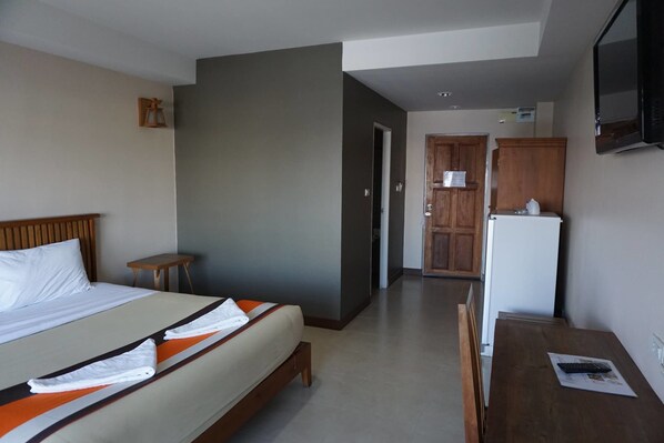 A hotel room with a bed, a small table, a refrigerator, and a television.