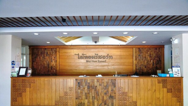 A reception desk at Mai Hom Resort with a wooden design, a skylight, and a sign above it. - Maihom Resort Dechatiwong Bridge (Nakhon Sawan)
