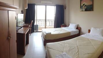 A hotel room with two beds, a desk, and a view of the balcony.