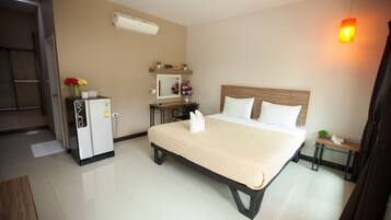 A hotel room with a bed, a desk, a refrigerator, a mirror, and a hanging light fixture.