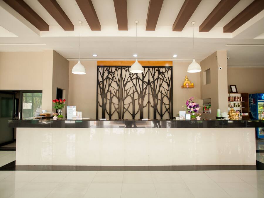 Zona de recepción con diseño moderno, que incluye un mostrador de recepción, iluminación colgante y un panel decorativo con motivos de árboles.