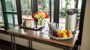 A breakfast bar with a tray of fruits, a vase of flowers, and a coffee maker. - MaiHom Villa (Nakhon Sawan)