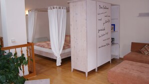 Un dormitorio con cama con dosel, un armario blanco y una mesita de noche.