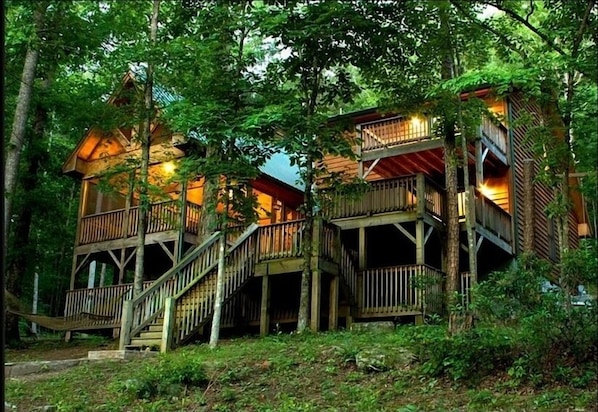 Una cabaña de madera de varios niveles construida en un área boscosa, con escaleras externas y balcones.