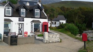 A white building with a red telephone booth, a post office sign, and a litter bin. - Sealladh na Mara (Gaelic for "View of the Sea") (Isle of Arran)