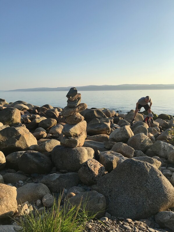 A rocky shoreline with large boulders and a person balancing a rock stack. - Sealladh na Mara (Gaelic for "View of the Sea") (Isle of Arran)
