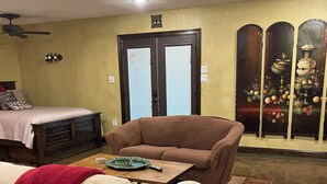 A living room with a sofa, a coffee table, and a dining table. There is a bed with a headboard and a wall-mounted light fixture. - Perfect for work or fun! 1 NIGHT RENTAL AVAILABLE! (College Station)