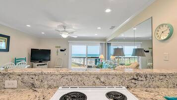 A kitchen with granite countertops, a white stove, and a large window overlooking the ocean.