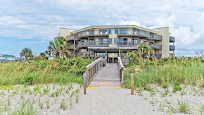 Un edificio fronte spiaggia con una passerella in legno che conduce all'ingresso.