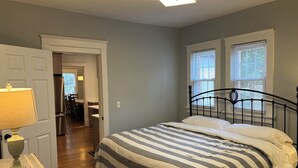 A bedroom with a bed, a lamp, a door, and a window.