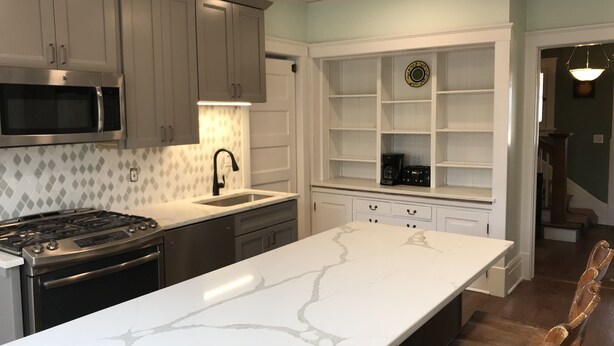 A modern kitchen with a large island, stainless steel appliances, and white cabinetry.