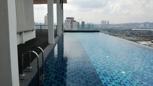 A rooftop infinity pool with a city view, surrounded by modern architecture.