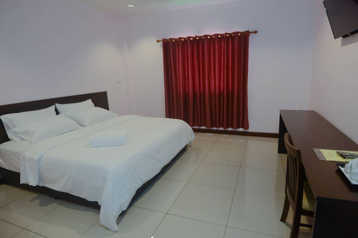 A hotel room with a bed, a desk, and a red curtain.