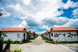 A row of white buildings with red roofs, a clear sky, and a pathway leading to a building in the distance. - Nangrong Garden Home (Nang Rong)