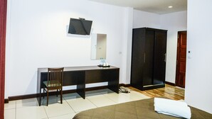 Hotellihuone, jossa on sänky, työpöytä tuolilla, televisio, vaatekaappi ja peili.
