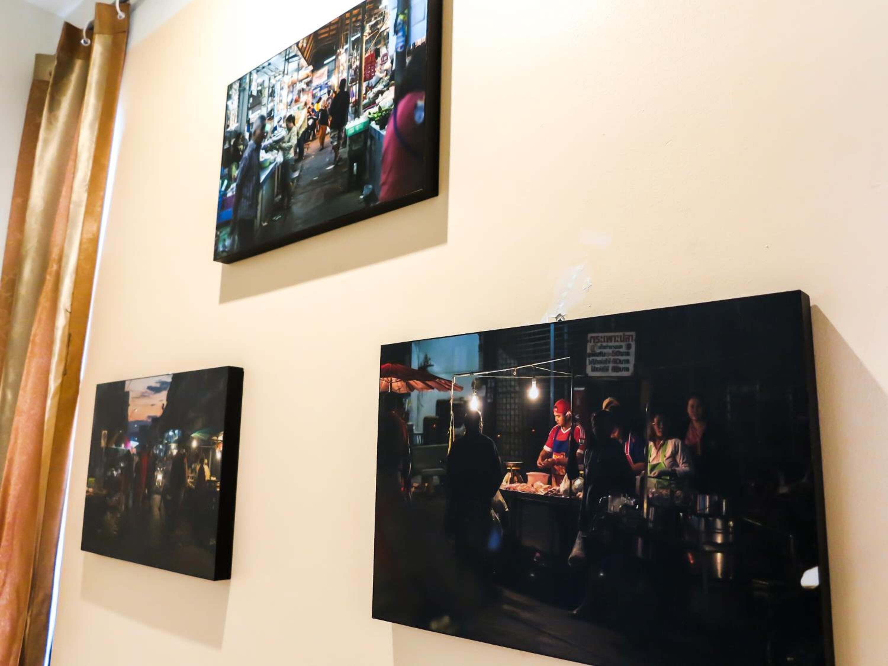 A wall with three framed photographs depicting busy market scenes.