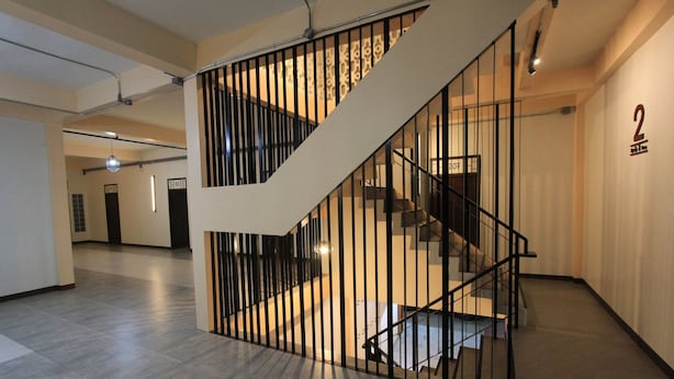 Een modern interieur met een trap, een bord met het cijfer '2' en een strak betegelde vloer.