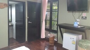 A hotel room with a TV, a small fridge, a trash bin, and a desk with a computer. - 339 Hotels & Resort (Nakhon Ratchasima)