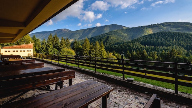 A terrace with wooden benches overlooking a mountainous landscape. - Hotel Boboty (Terchova)