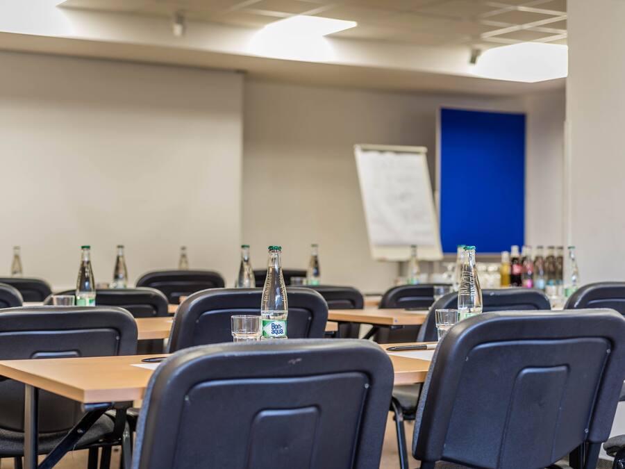 A conference room with tables, chairs, and water bottles.