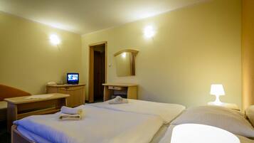 Ein Hotelzimmer mit Bett, Schreibtisch, Computer, Spiegel und Lampe.